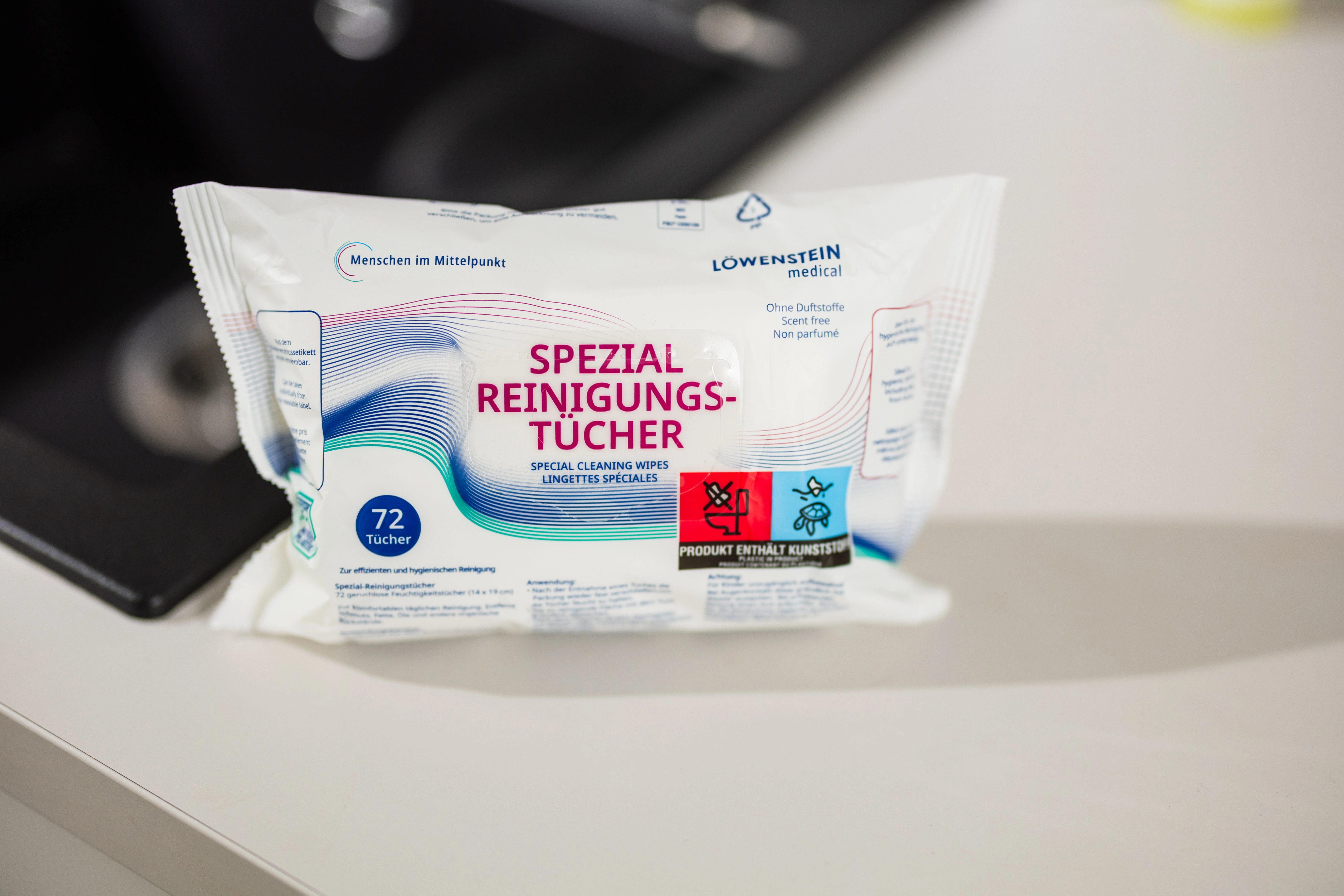 Spezial Reinigungstücher mit neutralem Geruch stehen in einer weißen Verpackung und blauen Farbelementen auf einer Küchentheke.